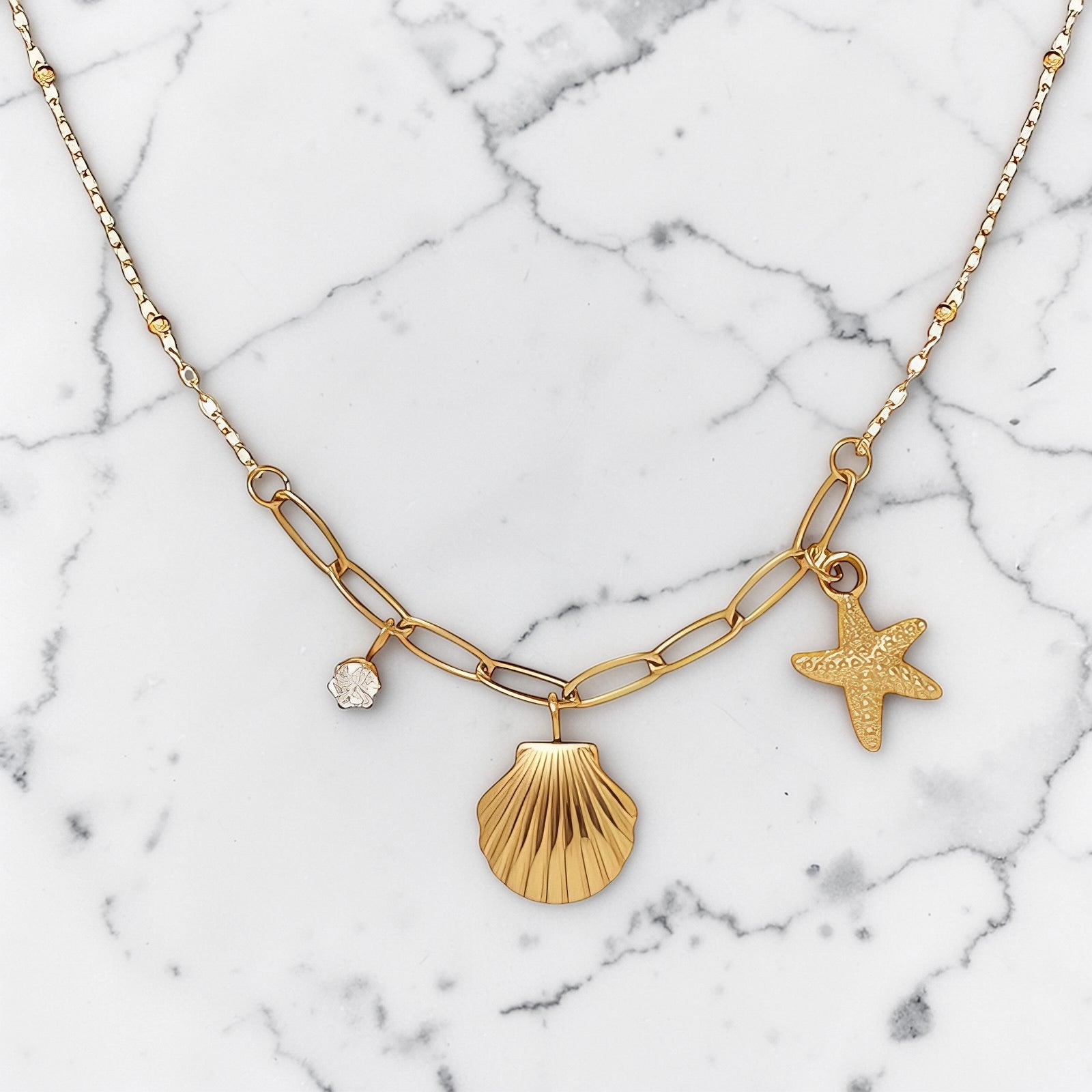 Gold shell pendant necklace with starfish and crystal charm on a mixed-link chain