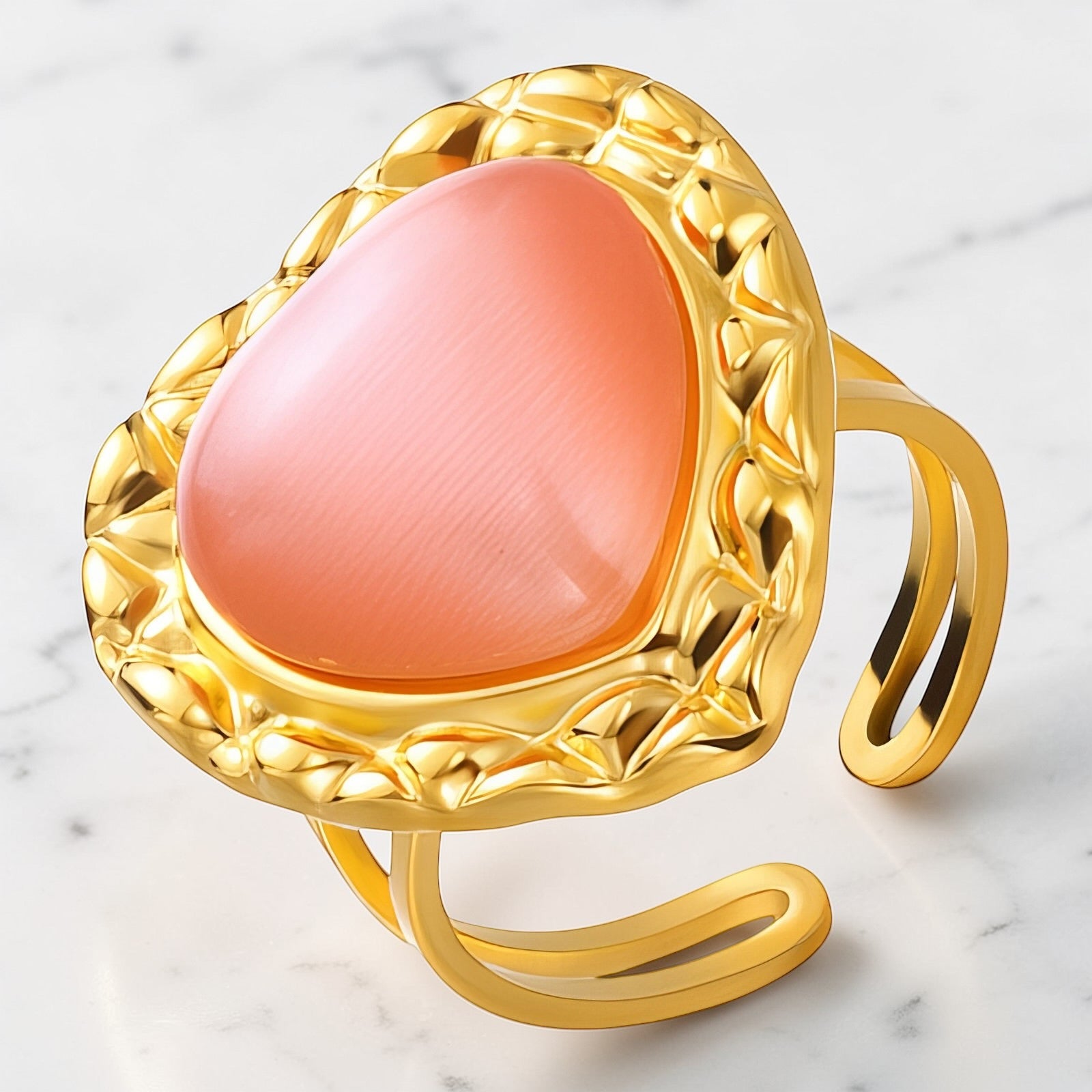 Gold open band ring with blush pink heart-shaped stone in textured setting