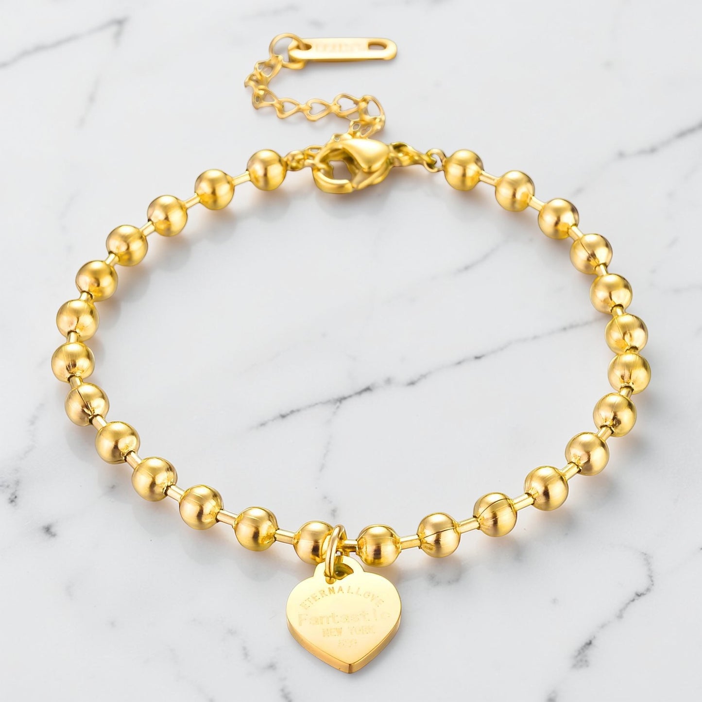 Gold beaded bracelet with a polished heart charm and adjustable clasp.