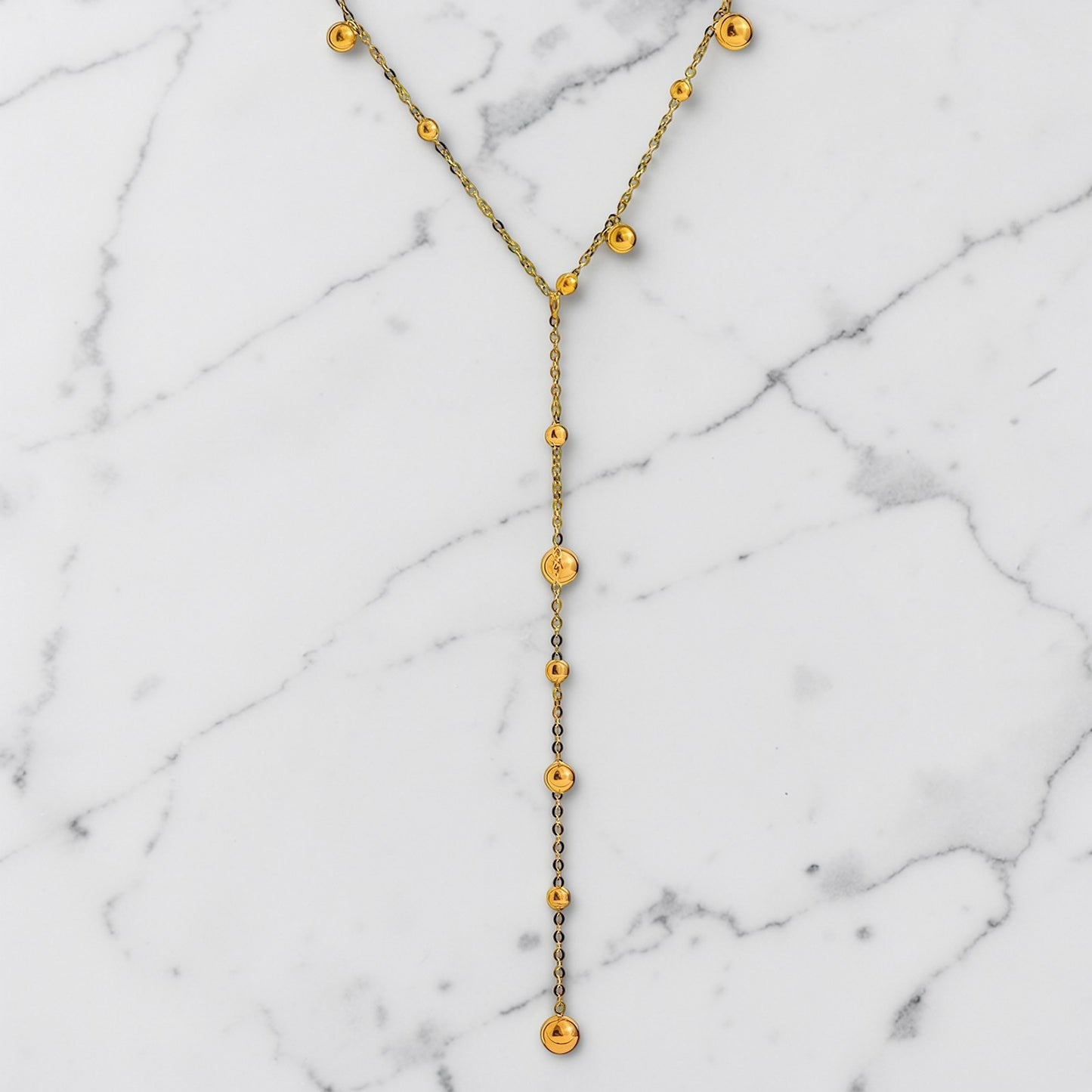 Gold-toned lariat necklace with delicate bead accents and a slim Y-shaped drop design.