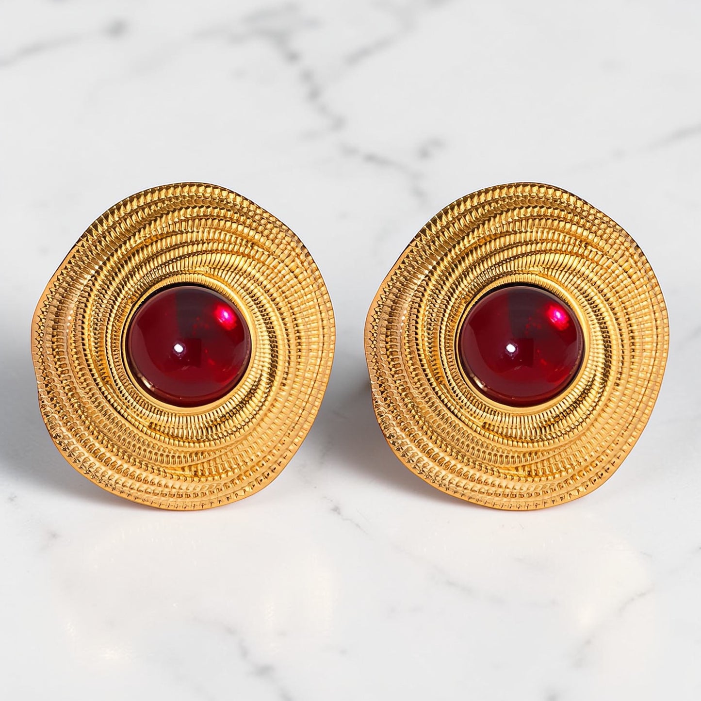 Gold textured earrings with deep red centre stone in a circular statement design