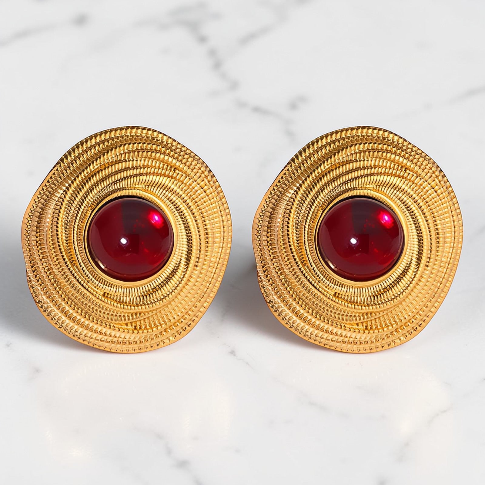 Gold textured earrings with deep red centre stone in a circular statement design