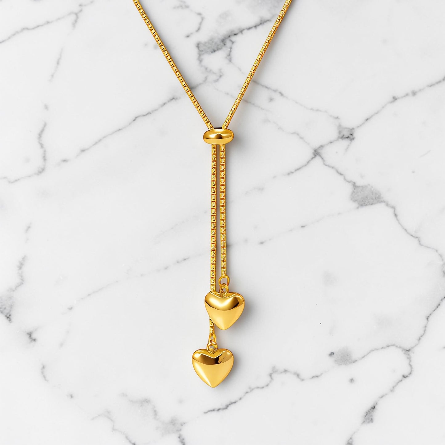 Gold adjustable necklace with two polished heart charms arranged in a vertical drop design.