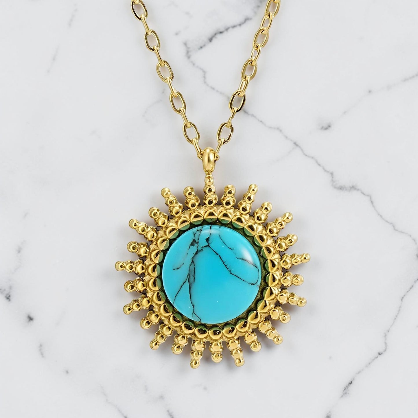 Gold sunburst pendant necklace featuring a round turquoise stone at the centre.