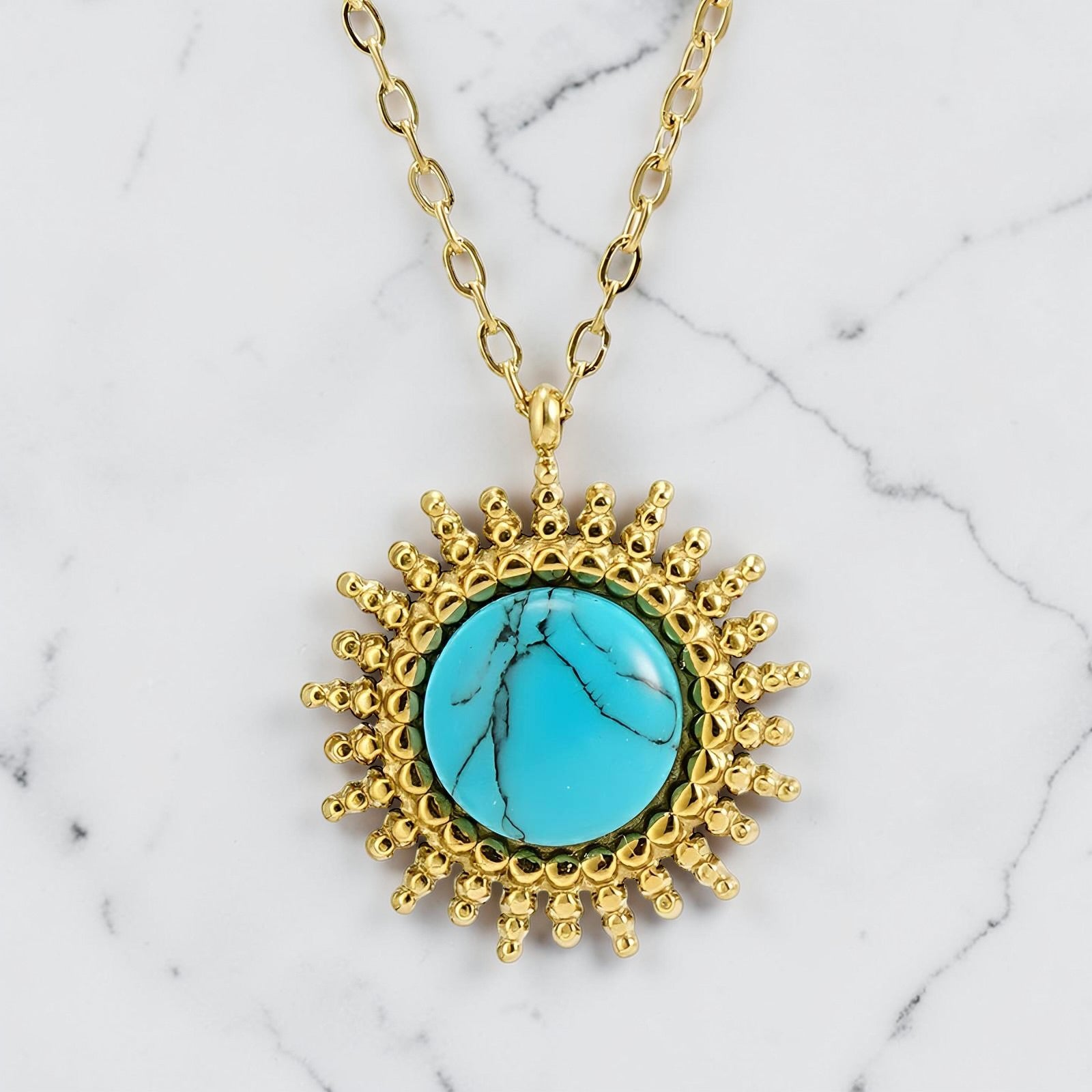 Gold sunburst pendant necklace featuring a round turquoise stone at the centre.