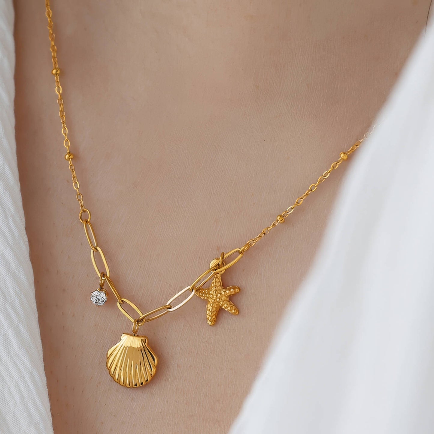 Gold shell pendant necklace with starfish and crystal charm on a mixed-link chain