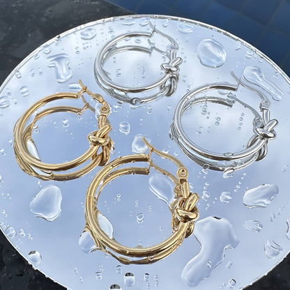 Gold hoop earrings featuring a polished infinity knot detail at the front.